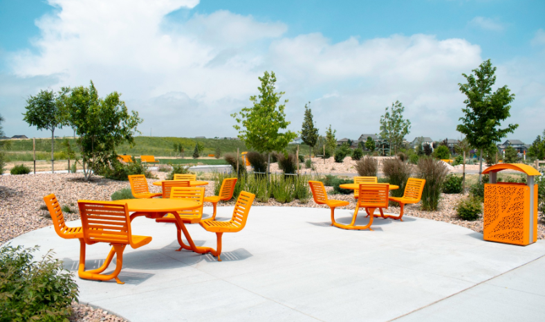 Orange Anova outdoor tables, chairs, and litter receptacle on a landscaped patio